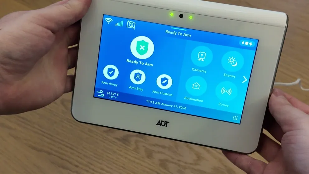ADT Command panel held in hand showing the home screen